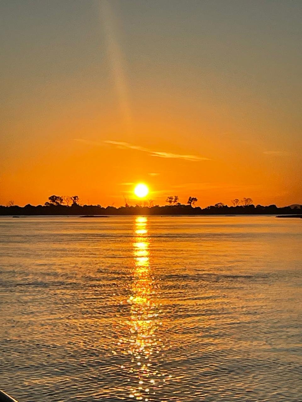 Rio ao entardecer, com o sol refletido na água